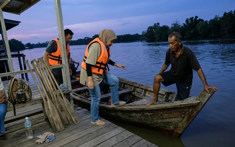 Guests boarding a traditional non-motorised sampan at a Kuala Selangor jetty at dusk
