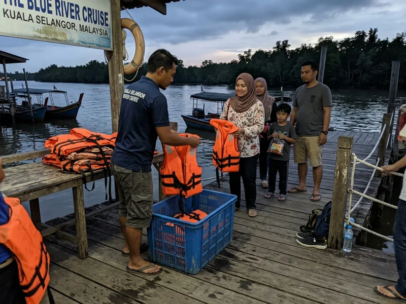 A guide checking life jackets at the wooden river jetty before an evening cruise
