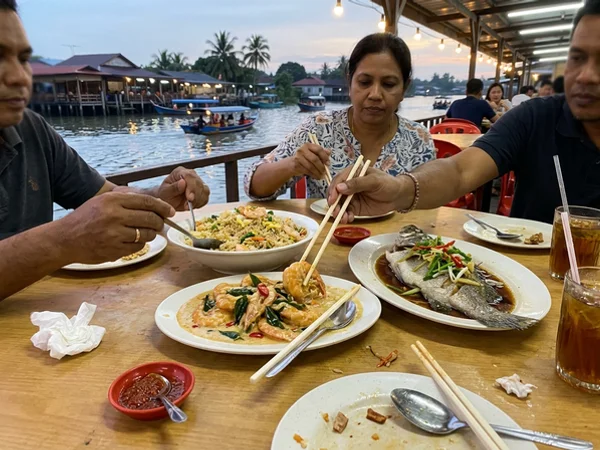 Shared seafood dinner at a riverside table at Pasir Penambang