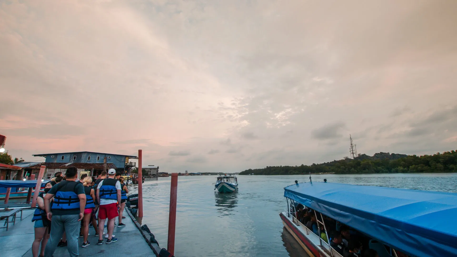 Guests in life jackets queuing on the jetty at dusk as a boat pulls away